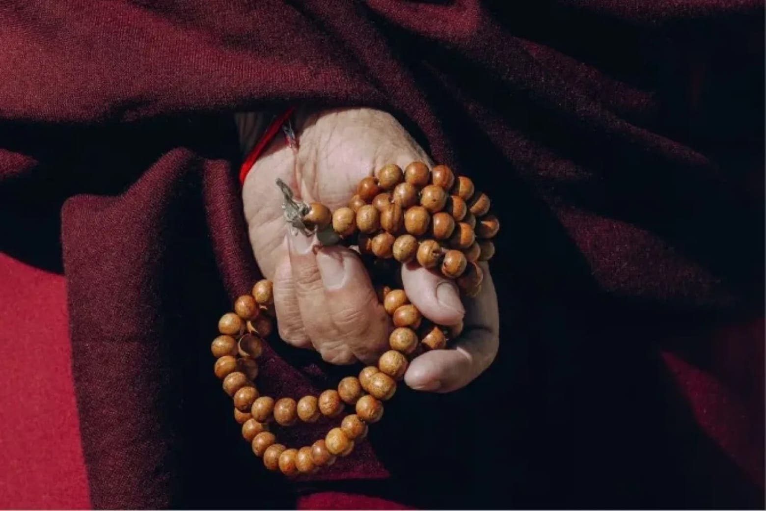 A monk's hand holding a strand of prayer beads