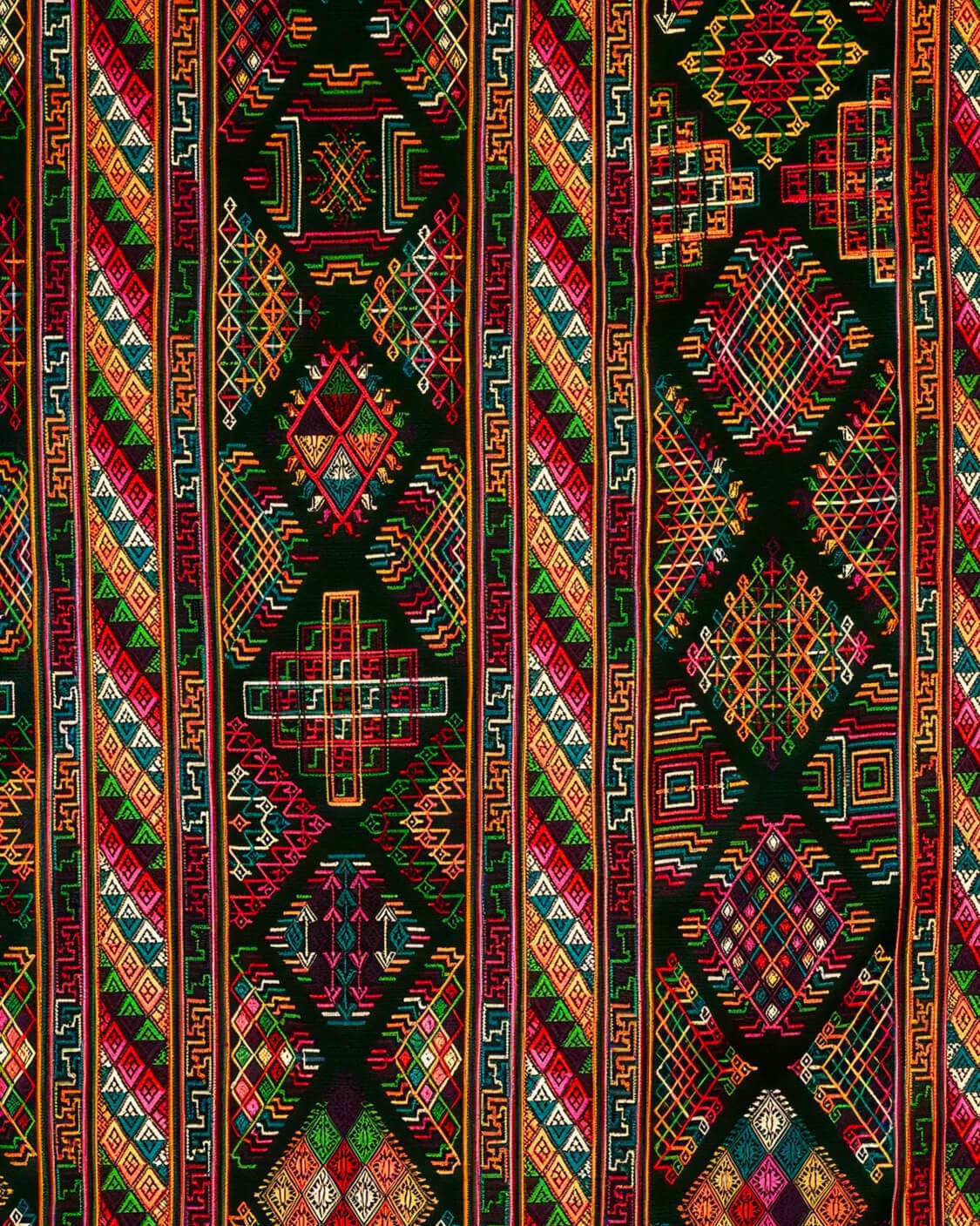 A close-up of a handwoven Bhutanese textile with intricate red, gold and turquoise geometric patterns.